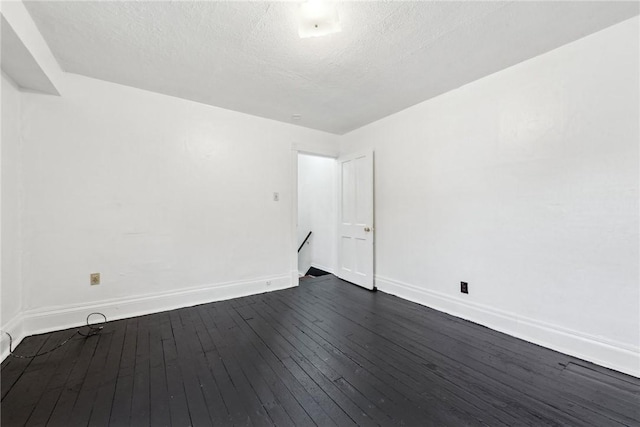 spare room with a textured ceiling and dark wood-type flooring