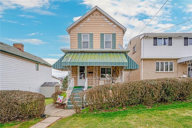 front facade featuring a front yard, a porch, and a storage unit