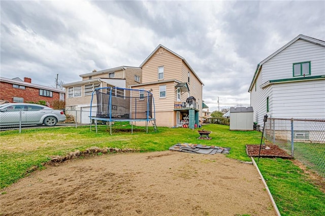 rear view of property featuring a trampoline and a lawn