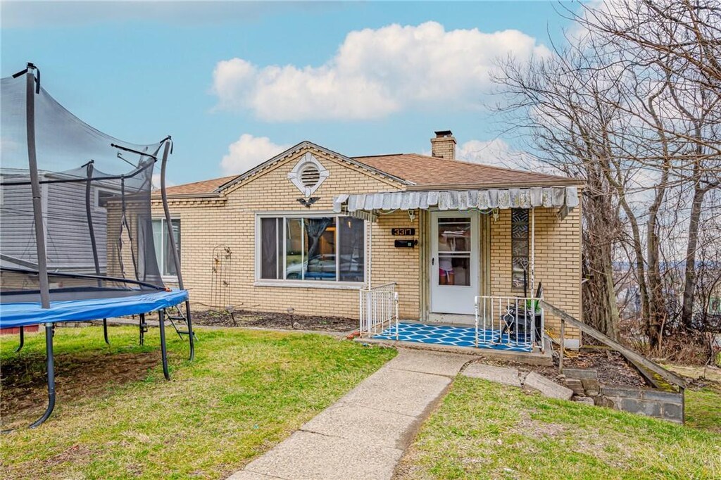 view of front of property with a trampoline and a front yard