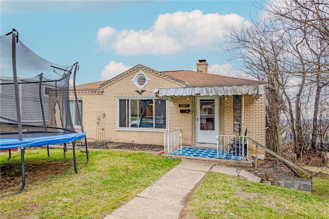 view of front of property with a trampoline and a front yard