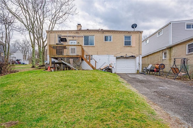 back of house featuring a garage, a wooden deck, and a lawn