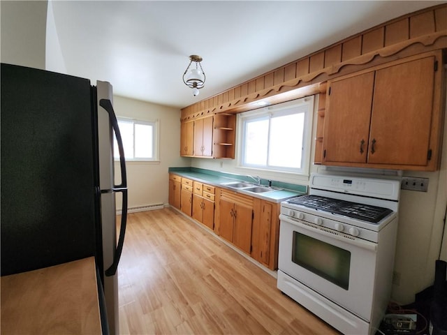 kitchen featuring black fridge, white gas range, a baseboard heating unit, sink, and light hardwood / wood-style floors