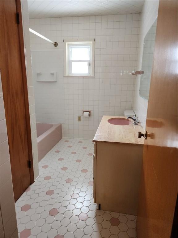 bathroom featuring tiled shower / bath, vanity, tile patterned floors, and tile walls