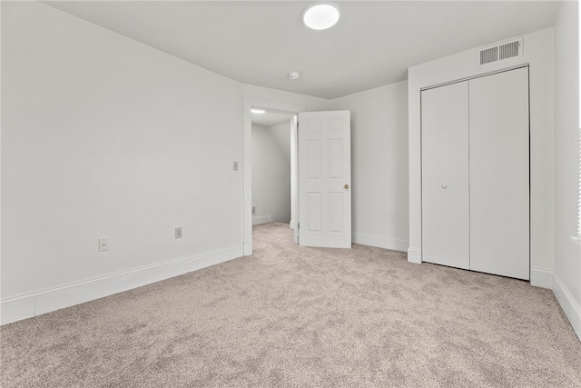 unfurnished bedroom featuring a closet and light colored carpet