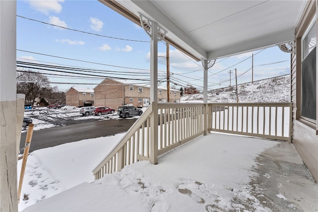 snow covered deck featuring a porch