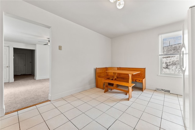 dining space featuring ceiling fan and light colored carpet