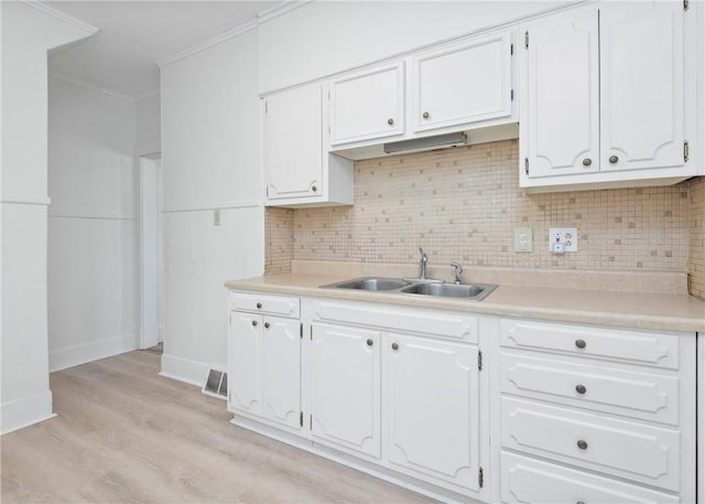 kitchen featuring white cabinets, decorative backsplash, light hardwood / wood-style floors, and sink