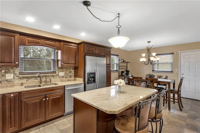 kitchen with sink, stainless steel appliances, an inviting chandelier, pendant lighting, and a kitchen island