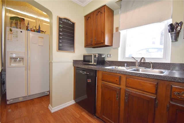 kitchen with light wood-type flooring, black dishwasher, white fridge with ice dispenser, and sink