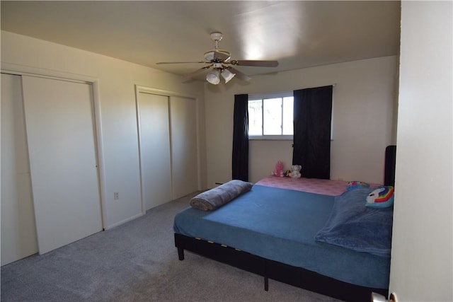 bedroom featuring light carpet, two closets, and ceiling fan