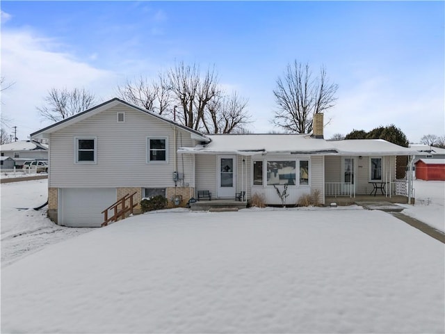 snow covered rear of property featuring a garage