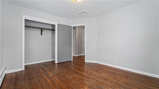 unfurnished bedroom with baseboard heating, dark wood-type flooring, and a closet