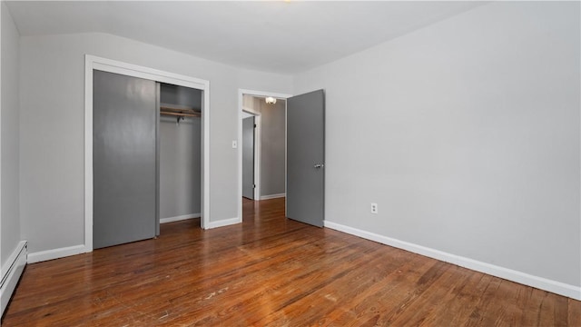 unfurnished bedroom featuring dark hardwood / wood-style floors, a baseboard heating unit, and a closet