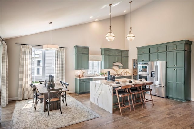 kitchen with a center island, stainless steel appliances, hanging light fixtures, and green cabinetry