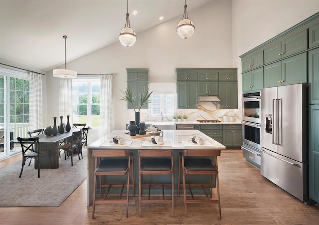 kitchen with decorative backsplash, a center island, stainless steel appliances, and decorative light fixtures