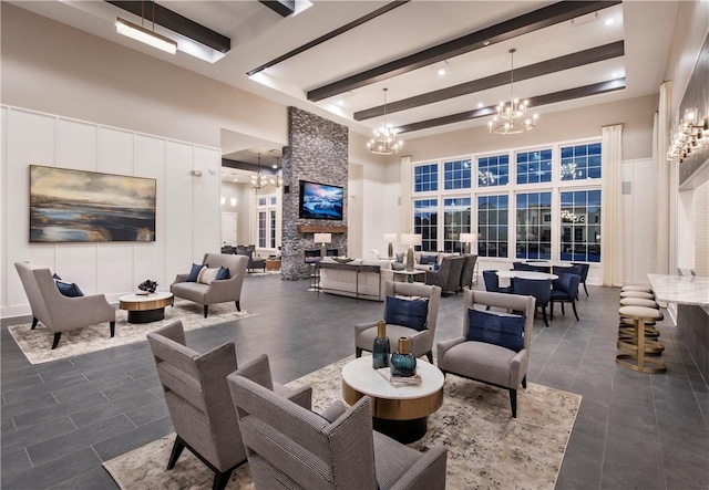 interior space with a fireplace, a towering ceiling, beamed ceiling, and an inviting chandelier