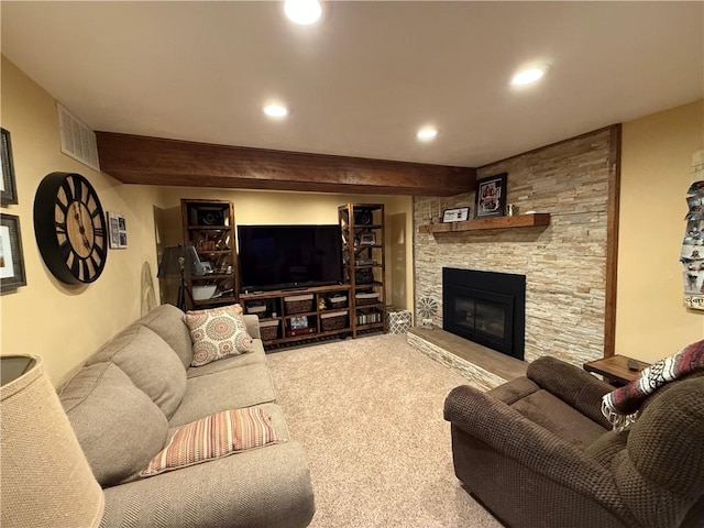 living room featuring beam ceiling, a stone fireplace, and carpet