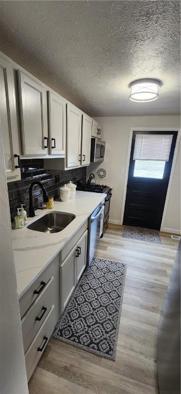 kitchen with sink, white cabinets, stainless steel appliances, and light hardwood / wood-style floors