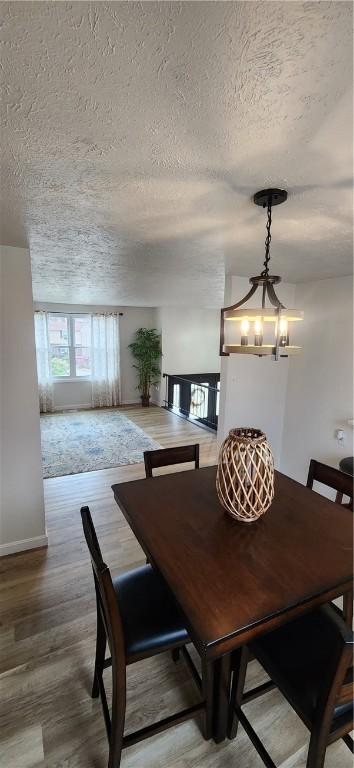 dining area featuring wood-type flooring, a textured ceiling, and an inviting chandelier