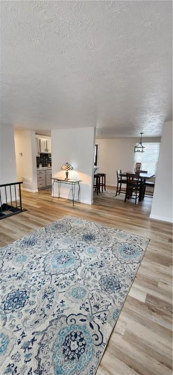 living room featuring a chandelier, a textured ceiling, and light hardwood / wood-style flooring