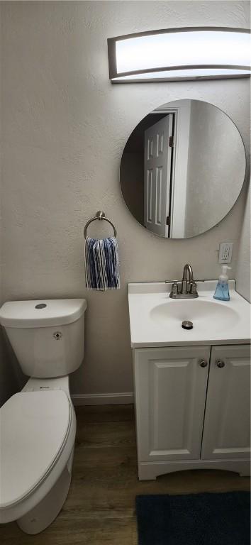 bathroom with hardwood / wood-style floors, vanity, and toilet