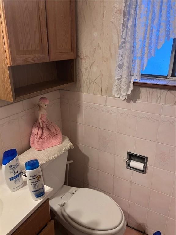 bathroom with vanity, tile walls, and toilet