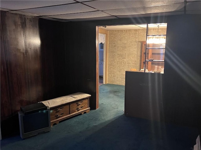 interior space featuring carpet flooring, a paneled ceiling, and wooden walls