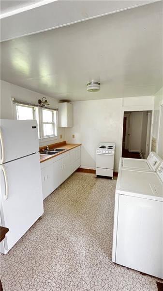 kitchen featuring white cabinetry, sink, white fridge, and washer and dryer