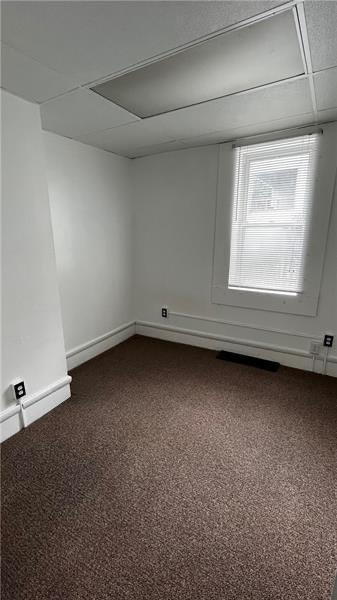 carpeted spare room with a drop ceiling