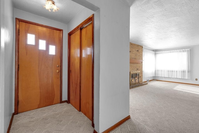 entryway featuring a textured ceiling, light colored carpet, and a brick fireplace