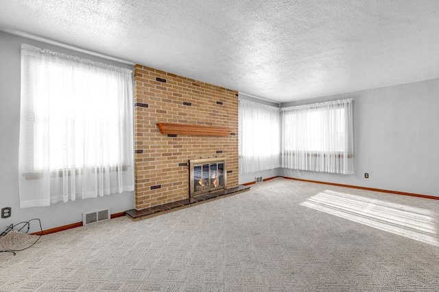 unfurnished living room with carpet floors, a textured ceiling, and a brick fireplace