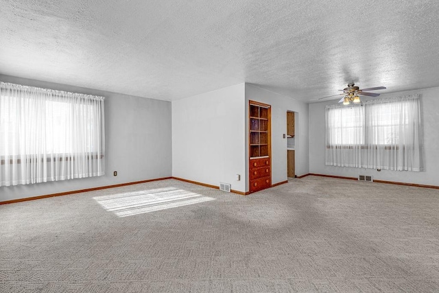 carpeted empty room featuring ceiling fan and a textured ceiling