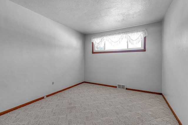 carpeted empty room featuring a textured ceiling