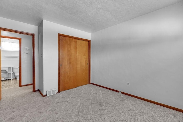 unfurnished bedroom featuring light carpet, a textured ceiling, and a closet