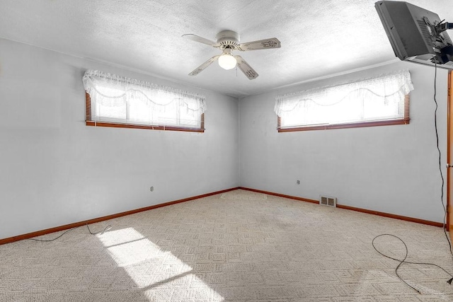 empty room featuring a textured ceiling, light colored carpet, and ceiling fan