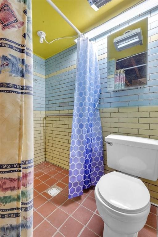 bathroom featuring tile patterned flooring, a shower with curtain, toilet, and tile walls