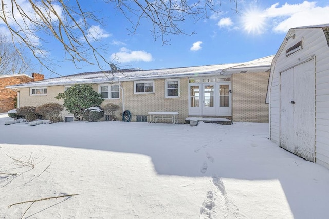 snow covered rear of property featuring french doors