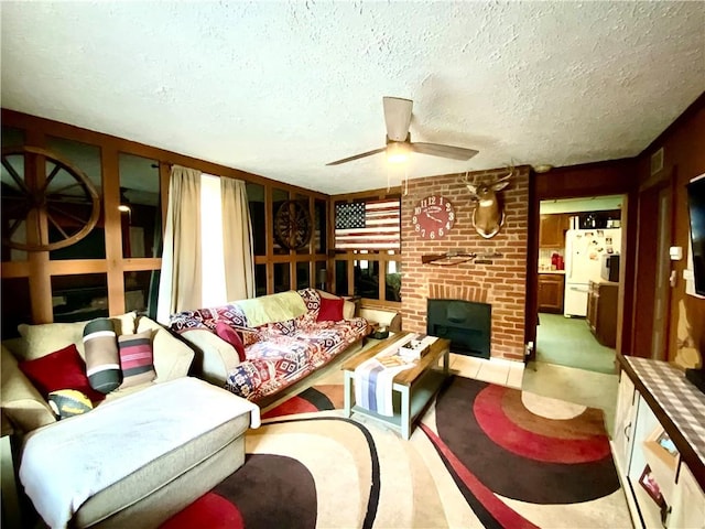 living room with ceiling fan, a textured ceiling, and a brick fireplace