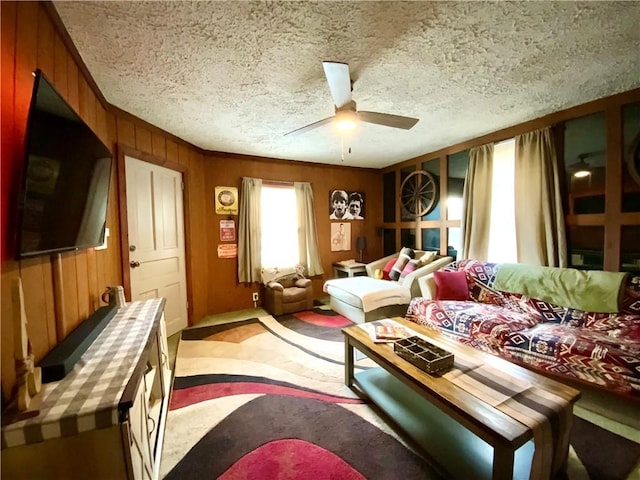 living room featuring wood walls, ceiling fan, light carpet, and a textured ceiling