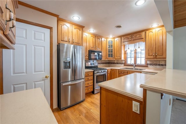 kitchen featuring sink, stainless steel appliances, kitchen peninsula, light hardwood / wood-style floors, and a breakfast bar