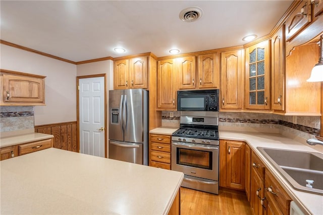 kitchen with sink, light hardwood / wood-style flooring, decorative backsplash, appliances with stainless steel finishes, and ornamental molding