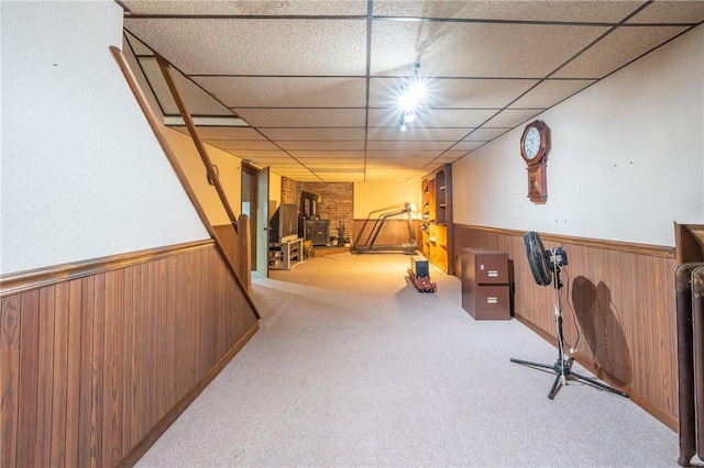 interior space with a wood stove, a paneled ceiling, and light colored carpet