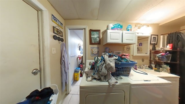 clothes washing area featuring separate washer and dryer, light tile patterned flooring, and cabinets