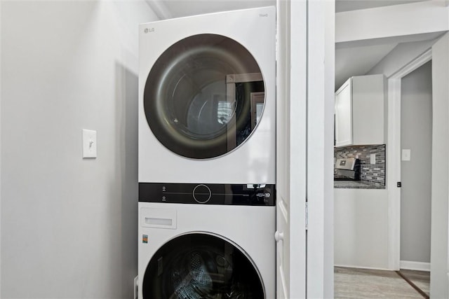 clothes washing area featuring light hardwood / wood-style floors and stacked washer / drying machine