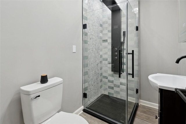 bathroom with hardwood / wood-style flooring, vanity, toilet, and a shower with door