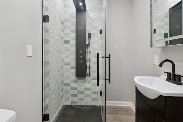 bathroom with hardwood / wood-style floors, vanity, toilet, and a shower with door