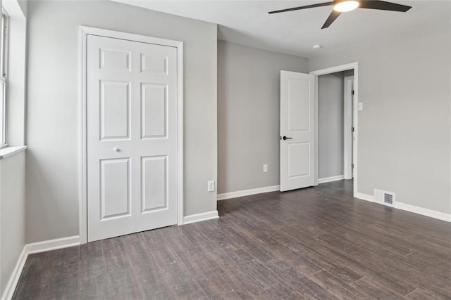 unfurnished bedroom with ceiling fan, a closet, and dark hardwood / wood-style floors