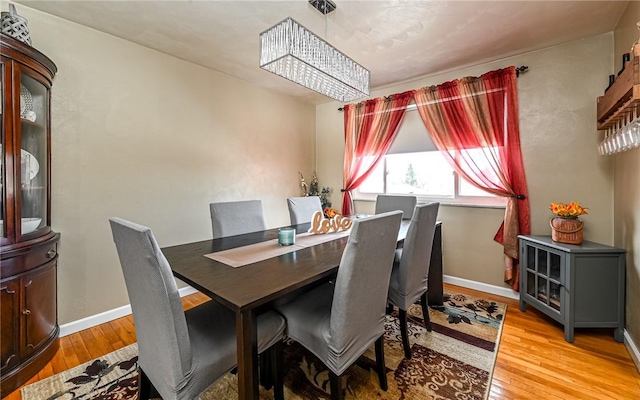 dining space with an inviting chandelier and light hardwood / wood-style flooring