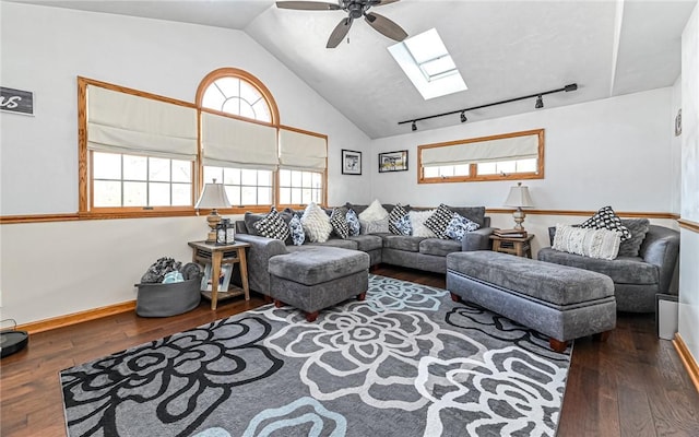 living room with dark hardwood / wood-style floors, ceiling fan, lofted ceiling with skylight, and rail lighting